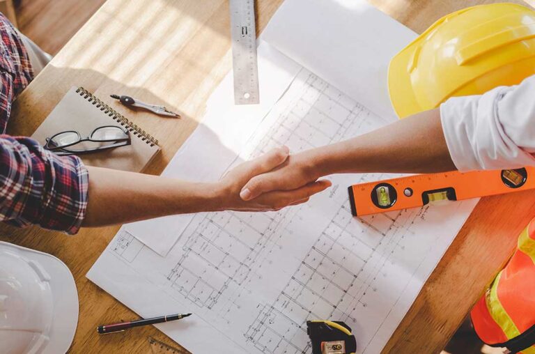 A contractor and homeowner reviewing construction plans and paperwork at a kitchen renovation site.