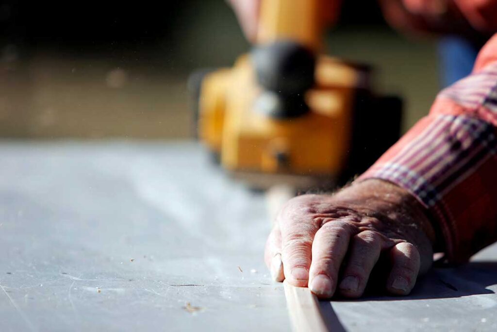Homeowners review renovation plans and material samples with a designer at a dining table.
