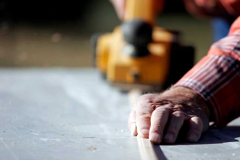 Homeowners review renovation plans and material samples with a designer at a dining table.